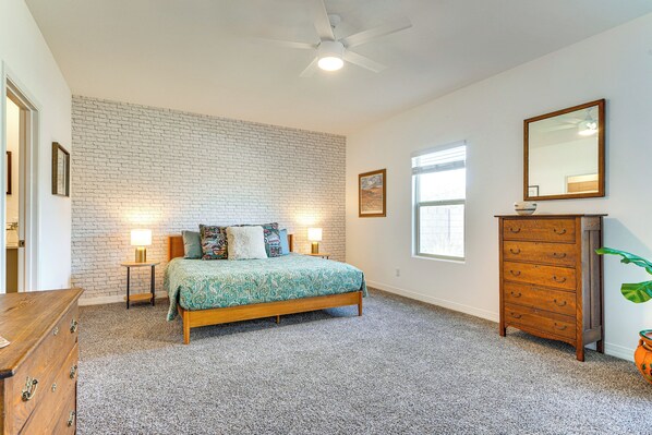 A bedroom with a bed, a dresser, a mirror, and a window. - Golf & Explore! Dove Mountain Desert Getaway (Marana)