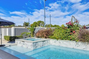 A swimming pool with a marble border, surrounded by lush greenery and flowering plants. - 7 Mi to Fremont St: Vegas Home w/ Backyard Oasis! (North Las Vegas)