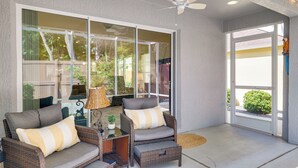 A patio area with wicker furniture, a ceiling fan, and a view through large glass doors. - Quiet Escape in The Villages! House w/ Lanai (Wildwood)