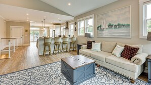 A spacious living room with a sofa, coffee table, and a painting of sailboats. - Explore the Seashore! Sunny Carolina Beach Home (Carolina Beach)