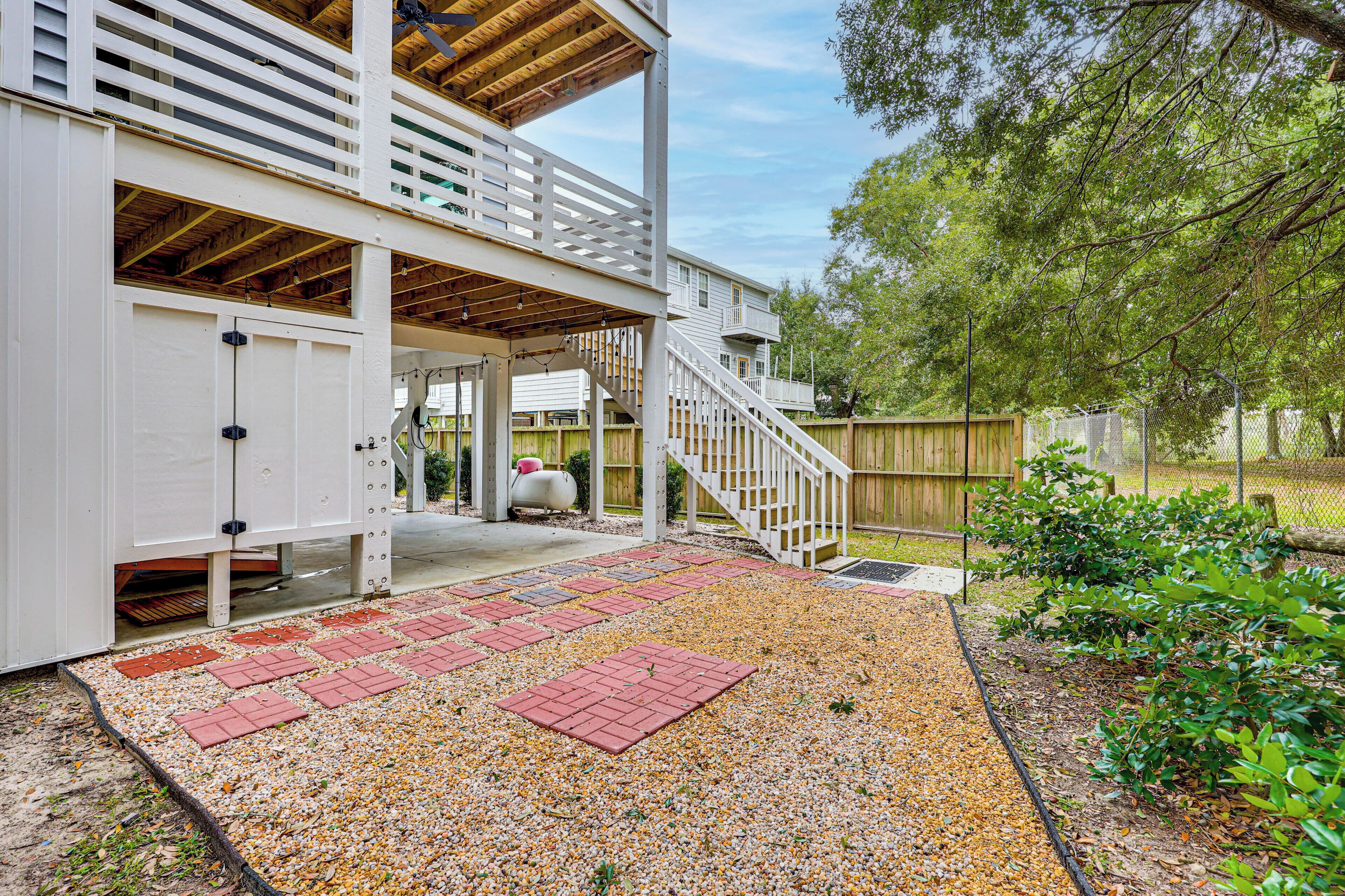 A covered outdoor area with a wooden deck, a staircase, and a gravel pathway.