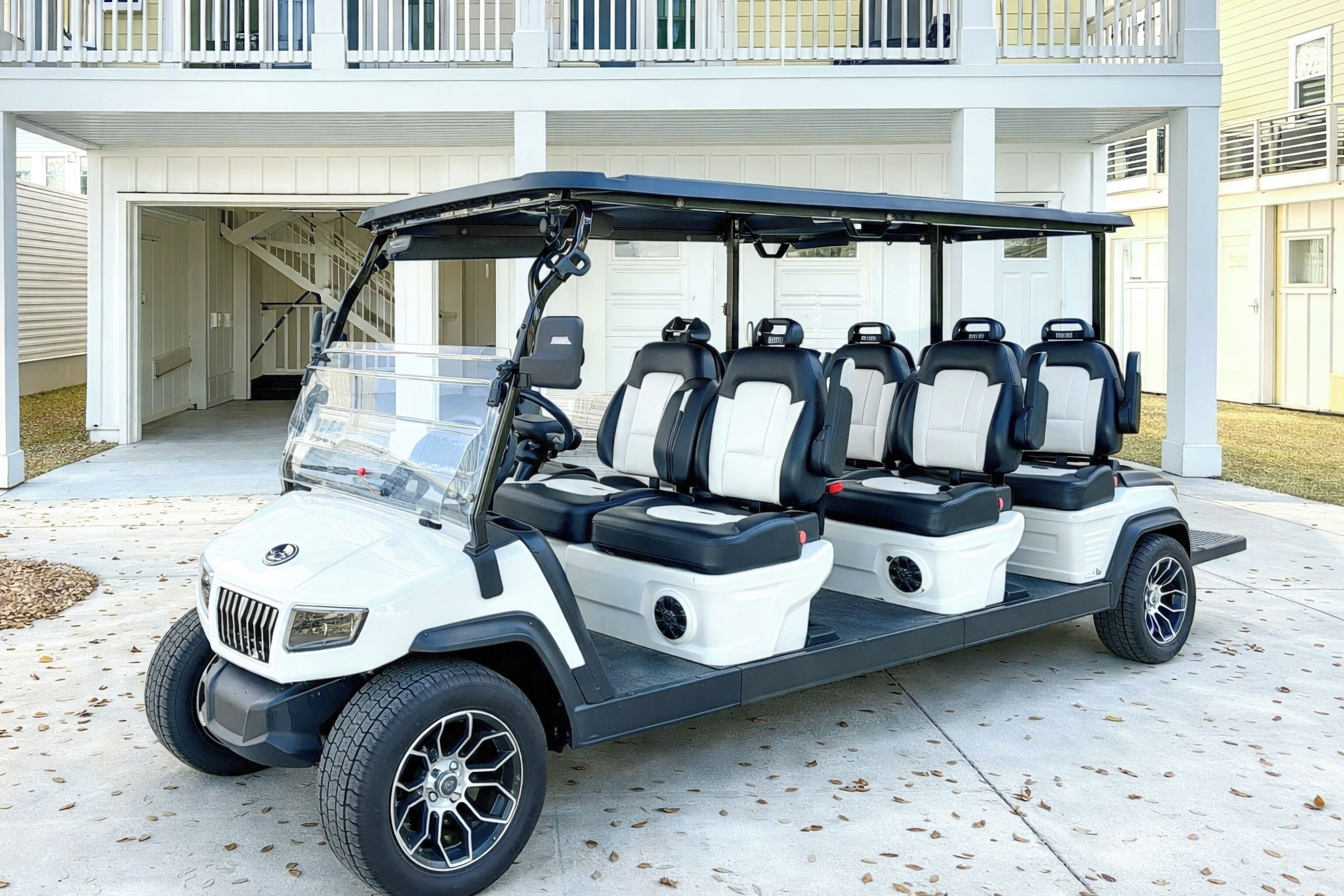 Un cart de golf amb diversos seients estacionat davant d'un edifici amb garatge.