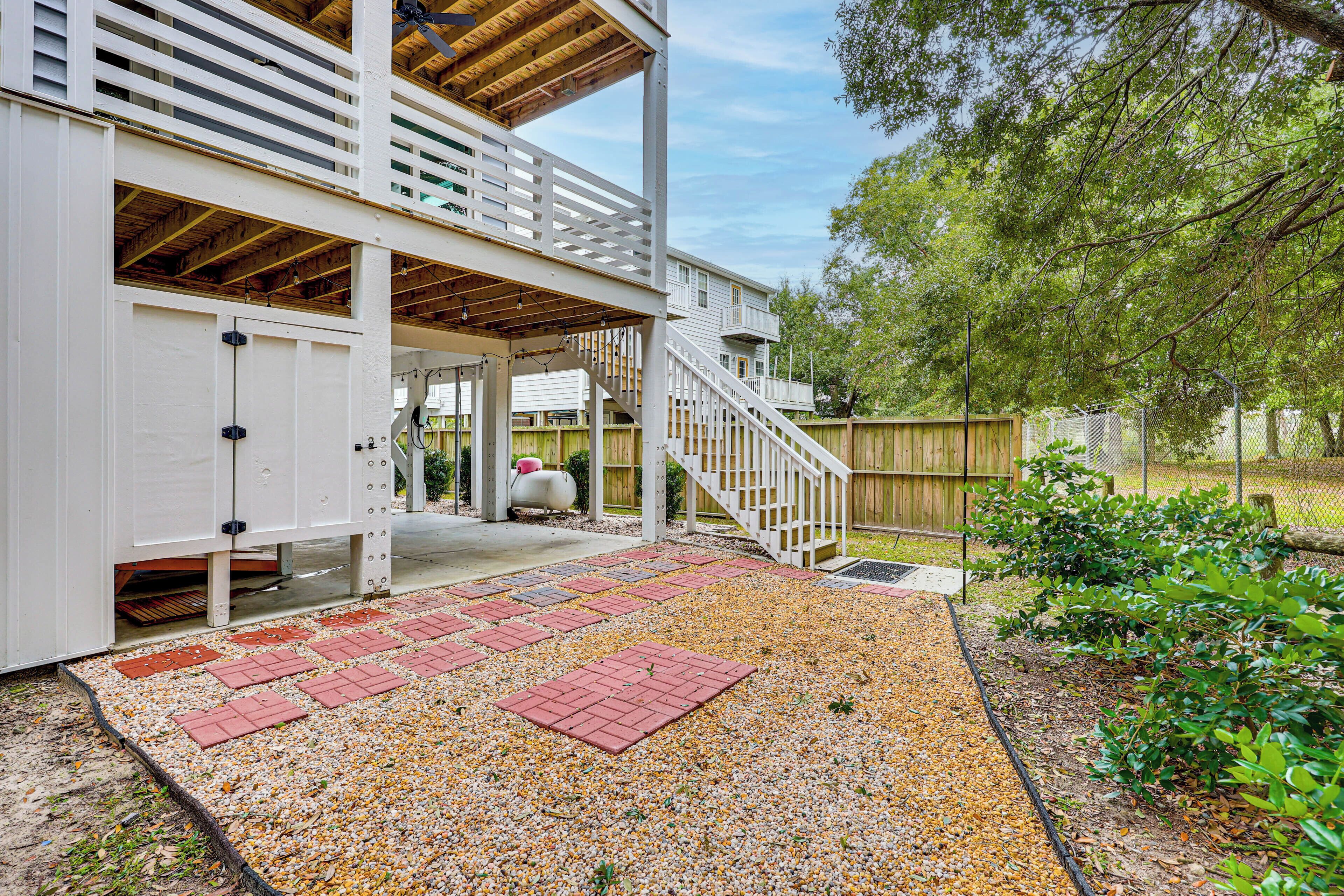 A covered outdoor area with a wooden deck, a covered staircase, and a gravel pathway.
