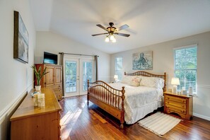 A bedroom with a wooden bed, a ceiling fan, a nightstand, and a window with blinds. - Peaceful Haven in Central Port Charlotte (Port Charlotte)