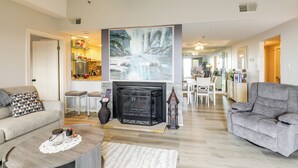 Ein geräumiges Wohnzimmer mit Kamin, Essbereich und einer Küche im Hintergrund.