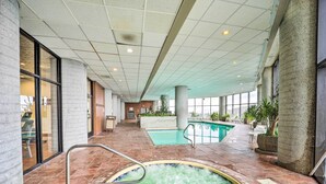 Ein Innenbereich mit Schwimmbecken, Whirlpool, Fliesenboden und großen Fenstern.