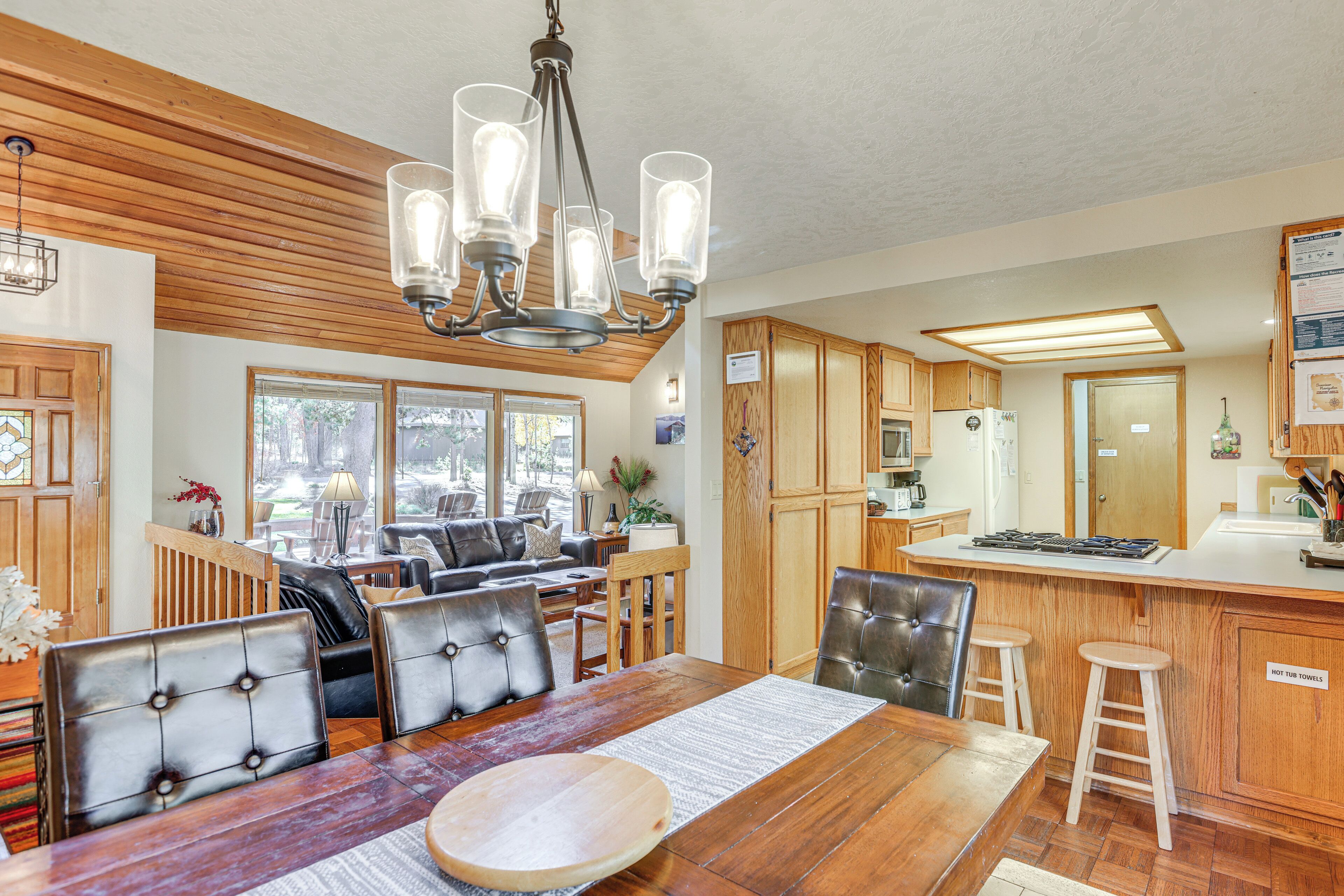 A spacious kitchen with wooden cabinets, a large island with stools, and a chandelier.