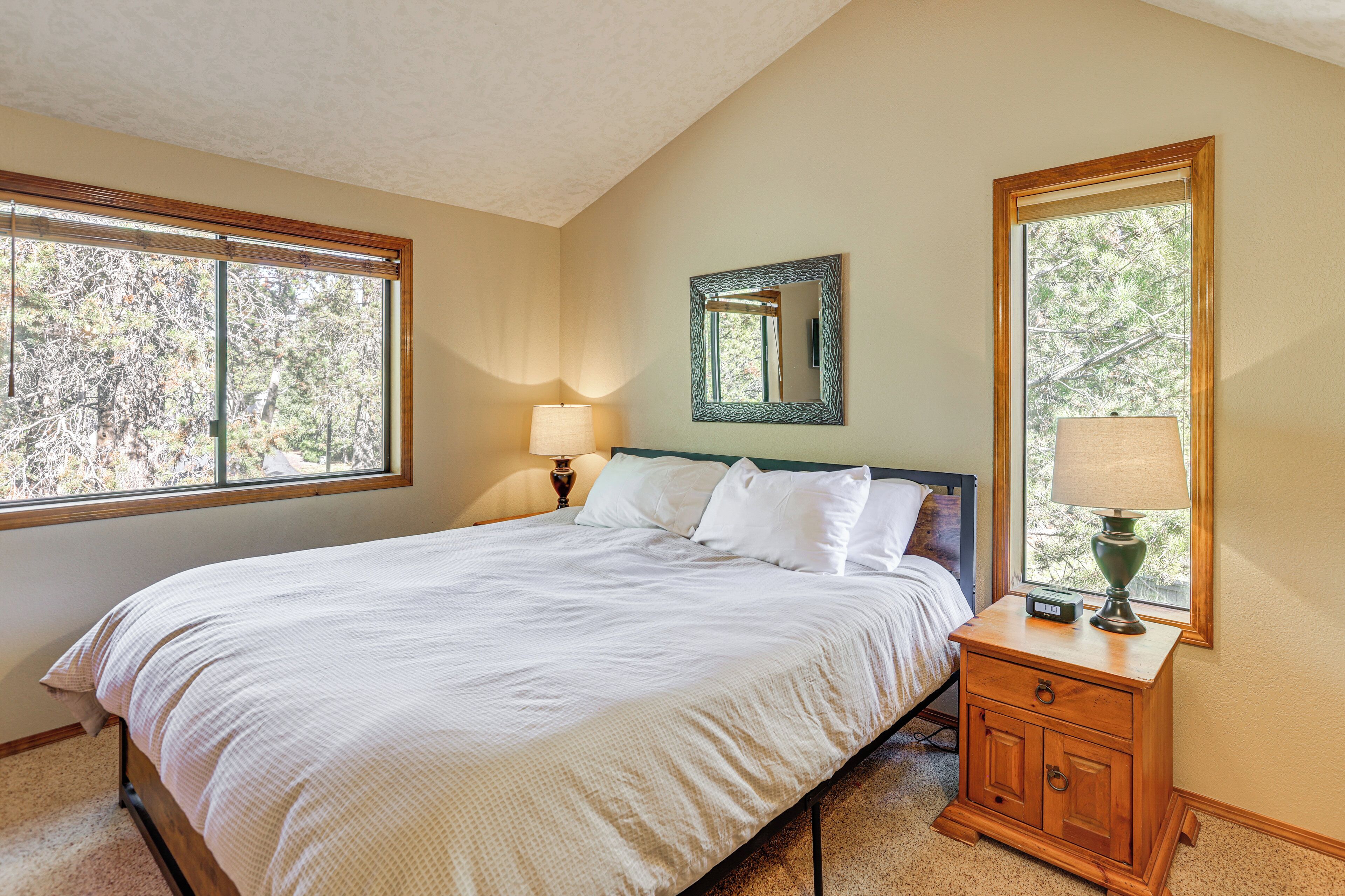 A neatly made bed with white linens, a bedside table with a lamp, and a mirror on the wall.