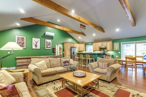 A spacious living room with a large sofa, a coffee table, and a dining area with a wooden table and chairs. - Year-round Loon Lake Retreat: Ski, Hike, Explore! (Chestertown)
