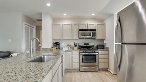 Una cocina moderna con encimeras de granito, electrodomésticos de acero inoxidable y armarios blancos.