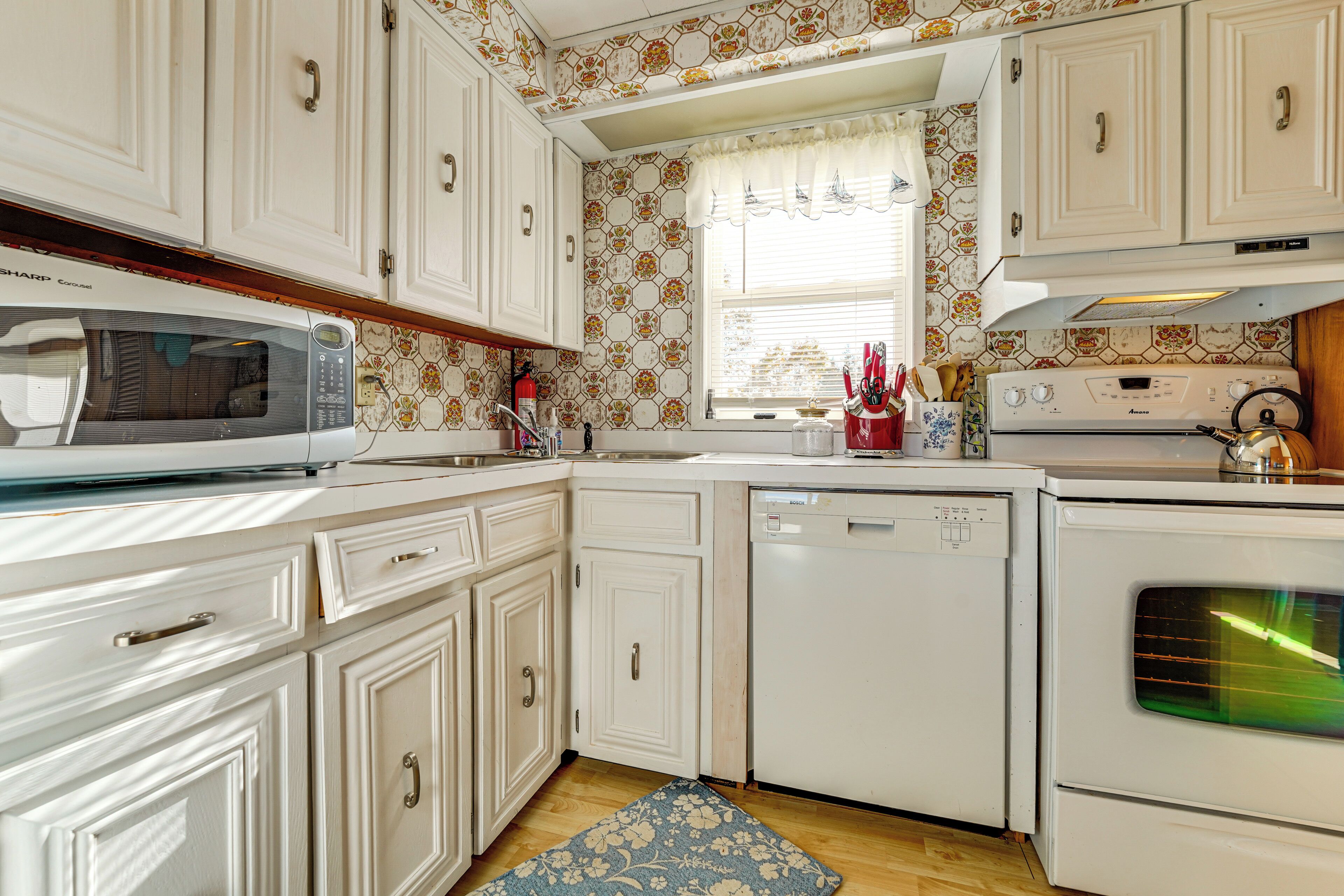 A kitchen with white cabinets, a microwave, a dishwasher, and an oven.