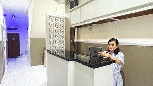A hotel room with a modern design, featuring a black countertop, a white cabinet, and a patterned wall. - Griya Inn (Tembalang)