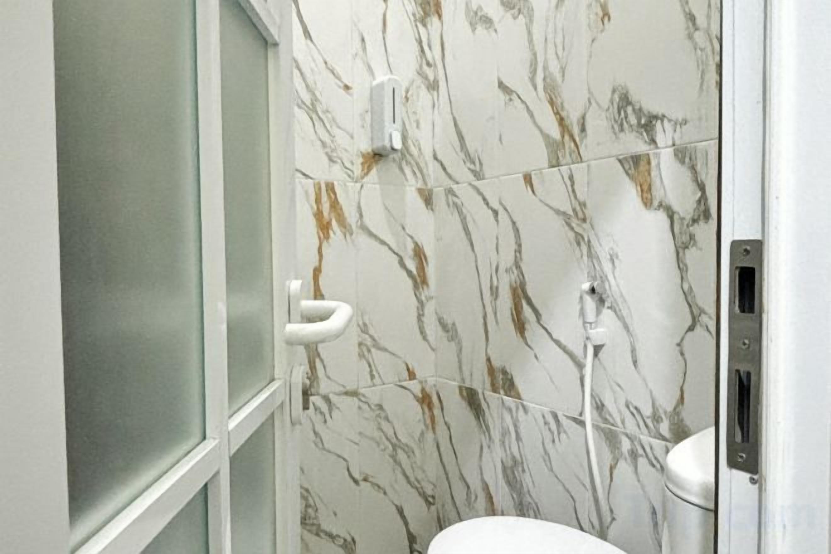 Ein Badezimmer mit Marmorwand, Toilette und Duschbereich.