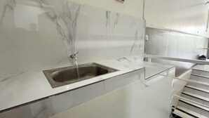 A bathroom with a marble sink, a mirror, and a white tiled wall. - Griya Inn (Tembalang)