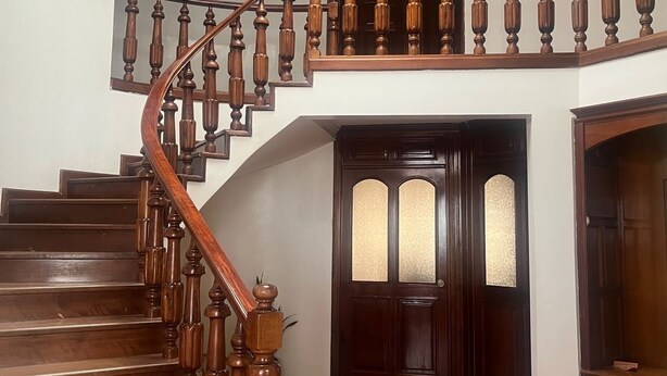 A grand staircase with wooden balusters and a dark wooden door with glass panels.