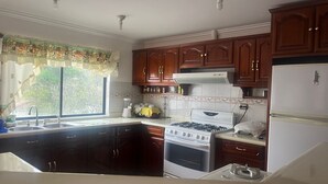 A kitchen with dark wooden cabinets, a white stove, and a refrigerator.