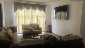 A living room with a sofa, a coffee table, and a TV mounted on the wall.