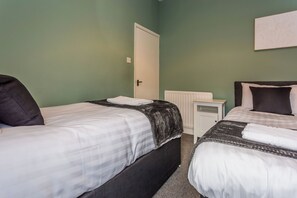 A bedroom with two beds, a white radiator, and a door. - Toast Stays - The Northern View (Sherburn Hill)