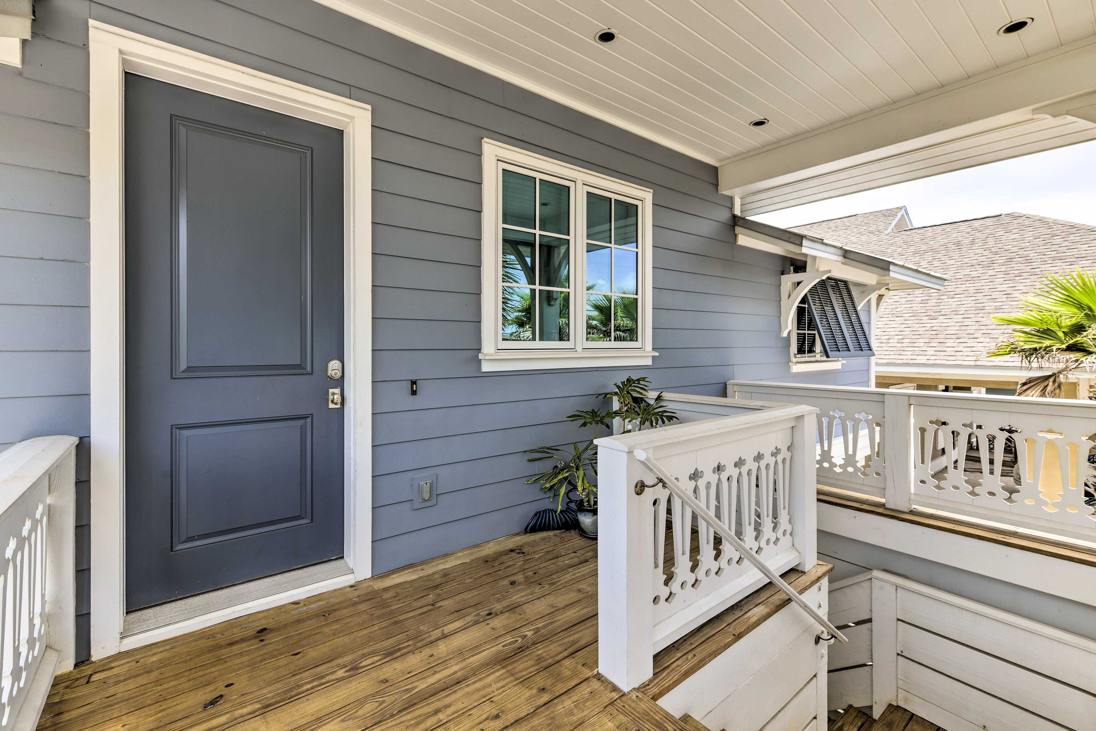 A grey door with a white frame, a window with white trim, and a wooden deck with white railings.