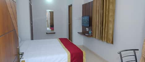 A bedroom with a bed, a TV, a mirror, and a wardrobe.