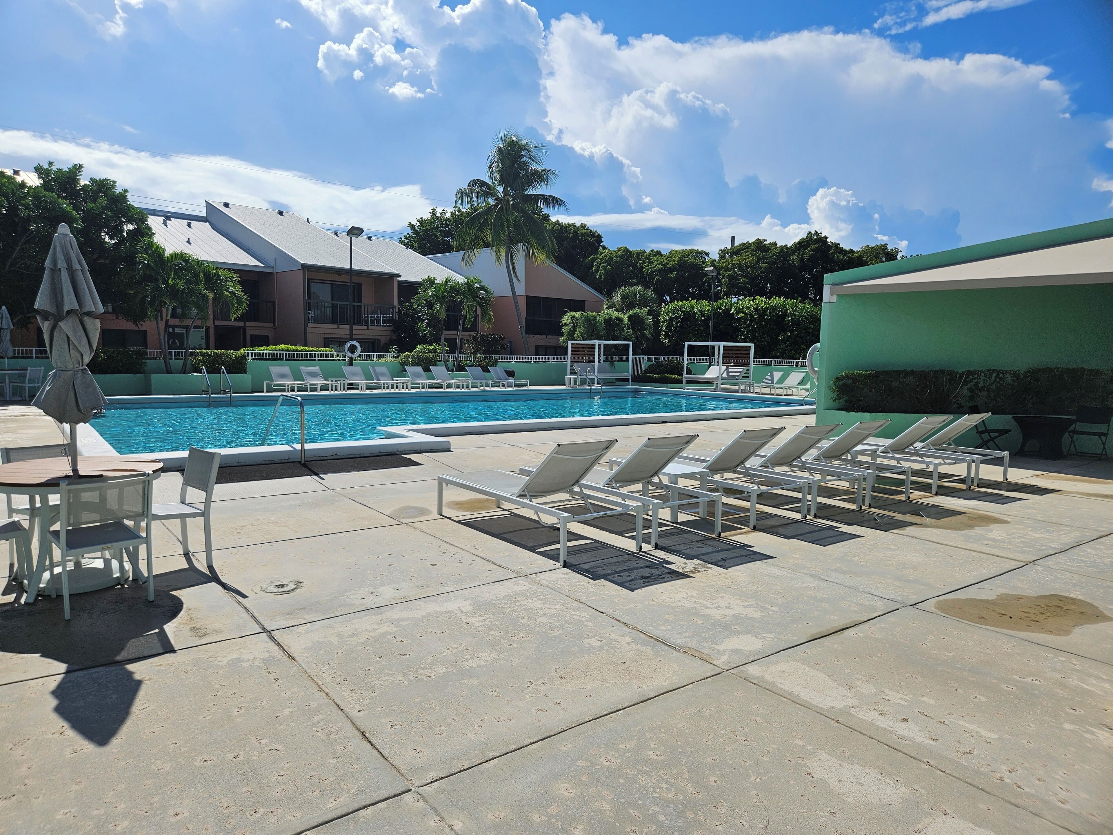 Un área de piscina con sillones reclinables, una mesa y sombrillas.