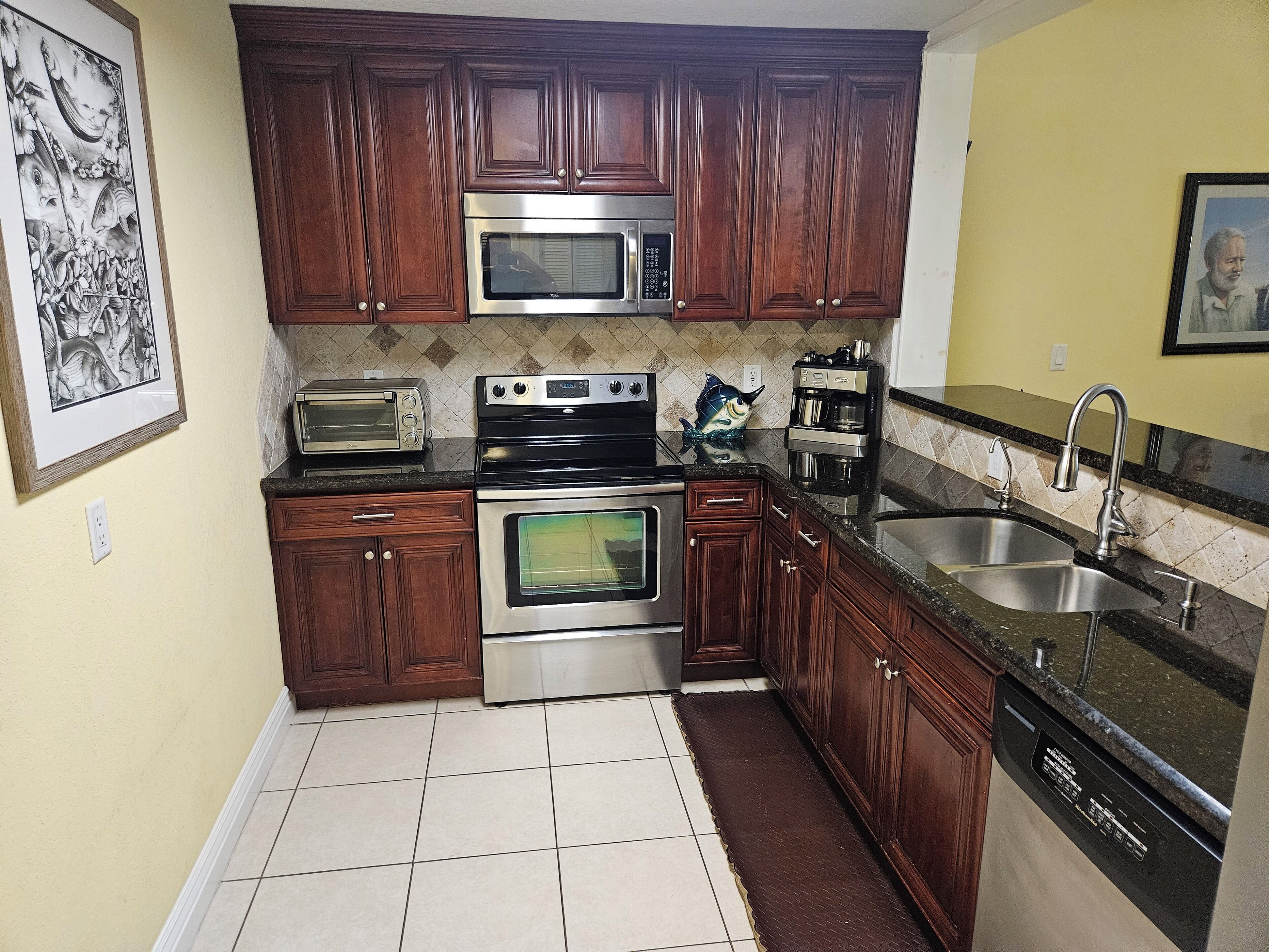 A kitchen with wooden cabinets, stainless steel appliances, a microwave, a toaster, and a sink.