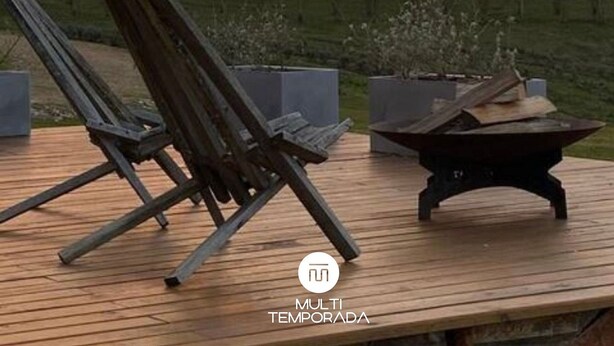A wooden deck with a lounge chair and a fire pit, overlooking a forest and a sunset. - Via Kairos - Rancho Queimado - SC (Rancho Queimado)