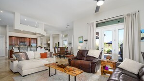 A spacious living room with a sofa, a leather armchair, and a coffee table. There is a dining area in the background with a table and chairs. - A Desert Oasis w/ 4 Peaks Mountain Views! (Scottsdale)
