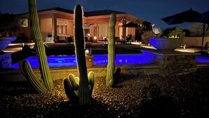 A nighttime view of a building with a pool and cacti in the foreground. - A Desert Oasis w/ 4 Peaks Mountain Views! (Scottsdale)