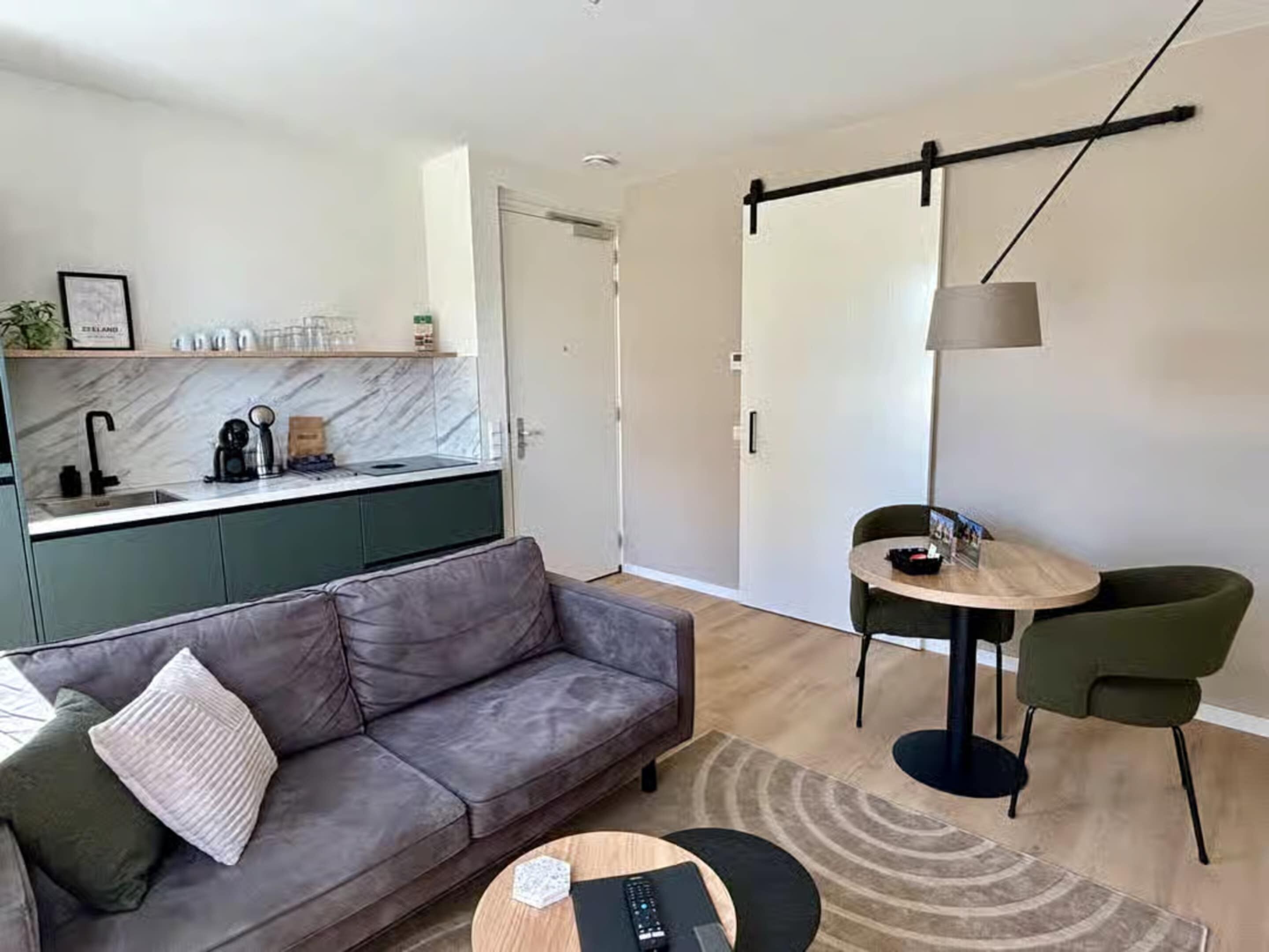A modern living room with a grey sofa, a round coffee table, and a dining area with a small table and chairs.