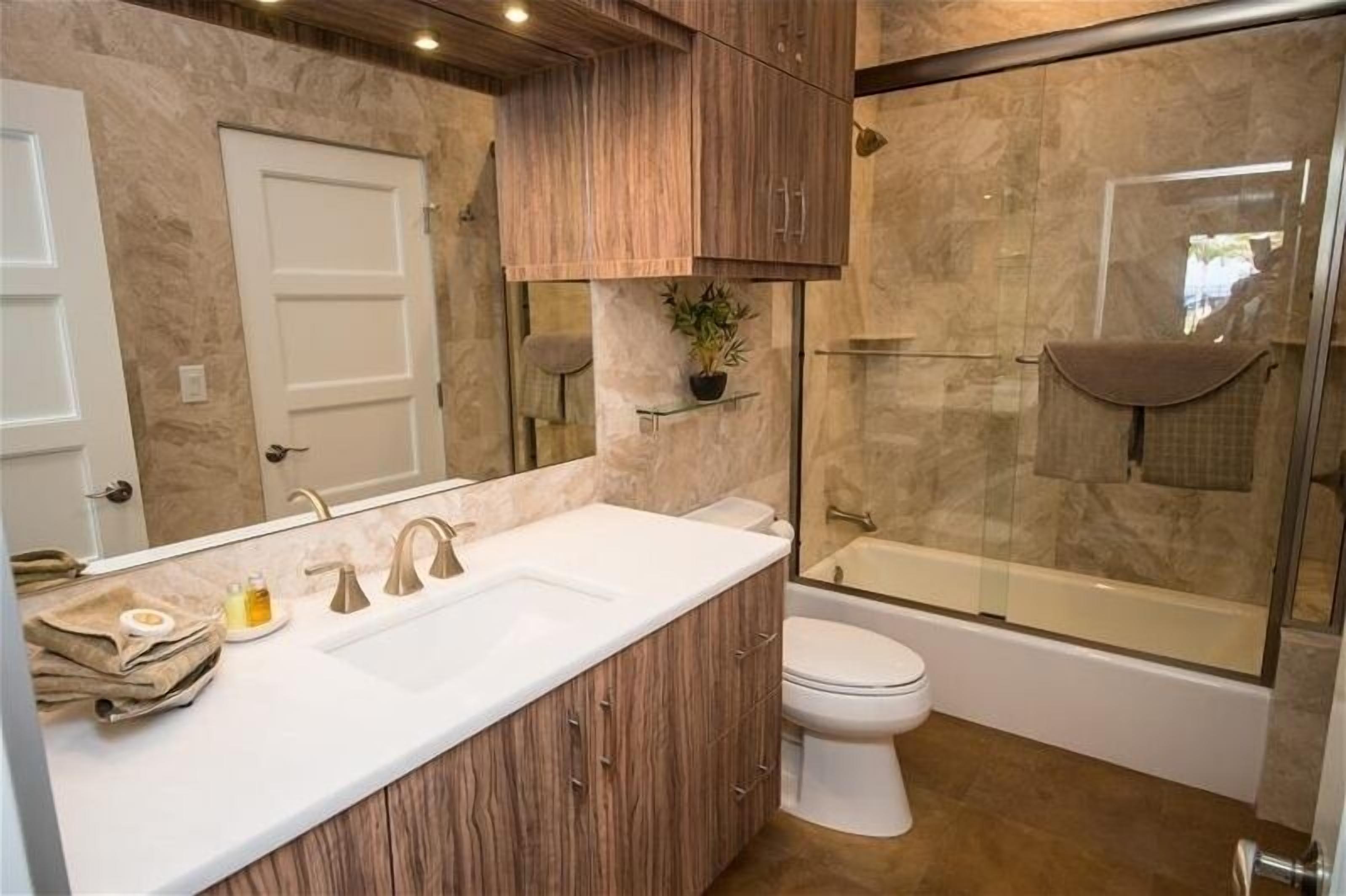 Un baño moderno con tocador de madera, un espejo grande, cabina de ducha de vidrio y un inodoro.