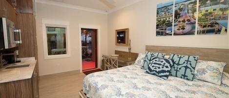 A bedroom with a bed, a desk, a chair, a TV, and a ceiling fan.