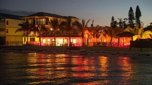 A beachfront hotel with multiple buildings, palm trees, and a reflective water surface. - The Rod and Reel Resort-Suite 2 (Anna Maria)