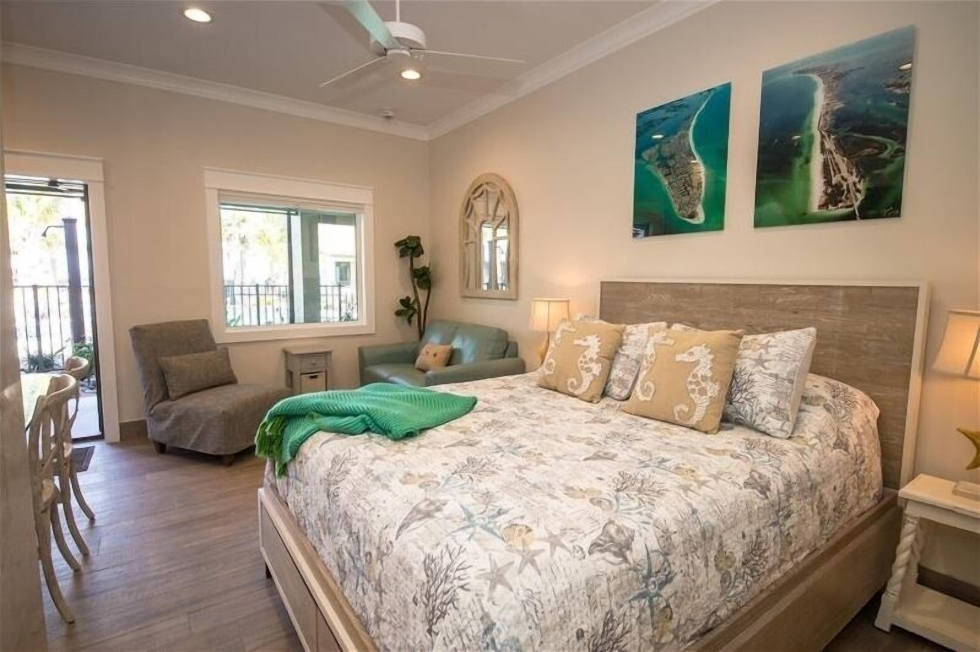 A bedroom with a large bed, a window, a chair, and a small table.