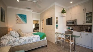 A bedroom with a bed, a desk, and a kitchenette. - The Rod and Reel Resort-Suite 3 (Anna Maria)