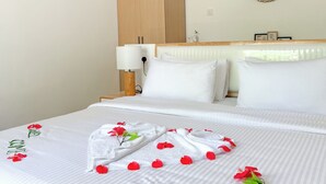 Una camera d'albergo con un letto rifatto, un armadio in legno, un comodino con una lampada e uno specchio decorativo appeso al muro.