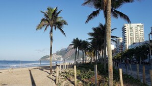 Ein Strand mit Palmen, sandigem Ufer und einer Küstenstadt im Hintergrund.