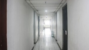 A long, narrow hallway with white walls and a tiled floor, leading to a bright area at the end. - Daddy's Room Apartemen City Park (West Jakarta)