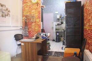A small office with a desk, chair, and shelves against a brick wall. - Daddy's Room Apartemen City Park (West Jakarta)