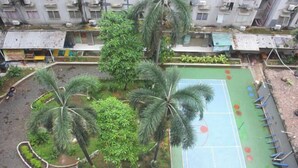 A courtyard with a basketball court, palm trees, and a small garden area. - Daddy's Room Apartemen City Park (West Jakarta)