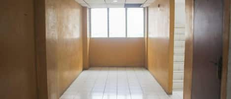 A corridor with tiled flooring, wooden walls, and a door at the end.