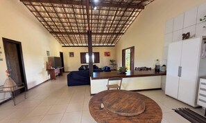 Un vaste espace de vie doté d’un plafond en bois, une cuisine avec un réfrigérateur blanc et une table à manger.