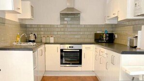 Eine moderne Küche mit weißen Schränken, einem grauen Sofa und einer gefliesten Spritzschutzwand.