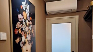 Ein Flur mit einem großen floralen Kunstwerk an der Wand, einer Tür mit Milchglasfüllung und einer darüber angebrachten Klimaanlage.