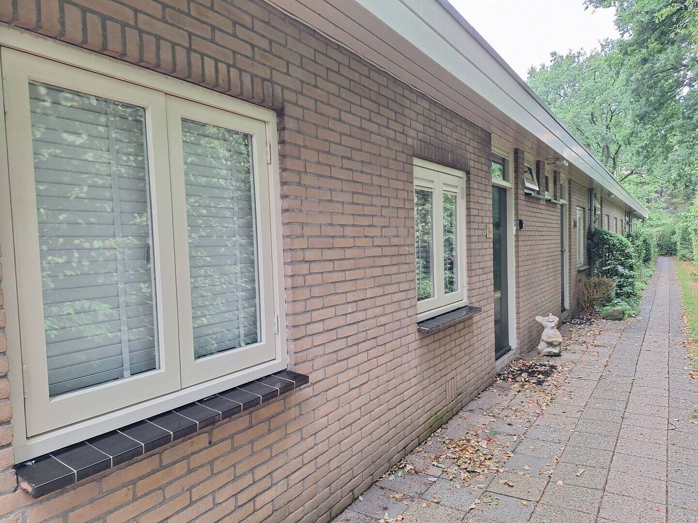Un bâtiment en briques doté de grandes fenêtres et d’un chemin menant à une porte.