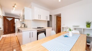 Eine moderne Küche mit weißen Schränken, einem Holztisch und einer Tischdecke mit Streifen.