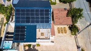 Ein Gebäude mit einer Solaranlage auf dem Dach, einem Schwimmbad und einer Terrasse aus Stein.