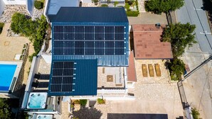 Una terraza con paneles solares, una piscina y un patio de piedra.