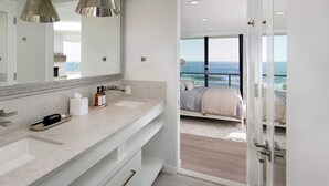 Une salle de bain moderne dotée d’un grand miroir, de deux lavabos et d’un meuble-lavabo avec des tiroirs de rangement.