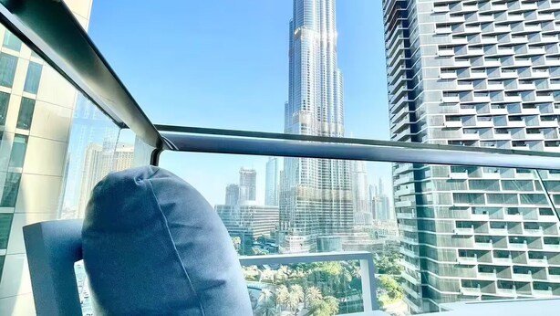 Una silla moderna con cojín, con vistas a un paisaje urbano con rascacielos, incluyendo el Burj Khalifa.